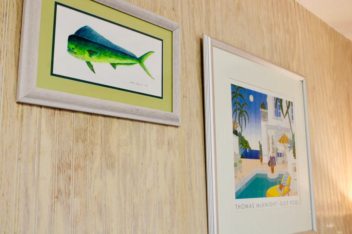 A playful and relaxed interior scene with framed aquatic artwork above, suggesting a beach-inspired ambiance. The room is bright and airy, inviting guests to unwind in a visually engaging and comfortable environment. While not a direct bathroom shot, the decor echoes the coastal lifestyle and ties in themes of relaxation and self-care.