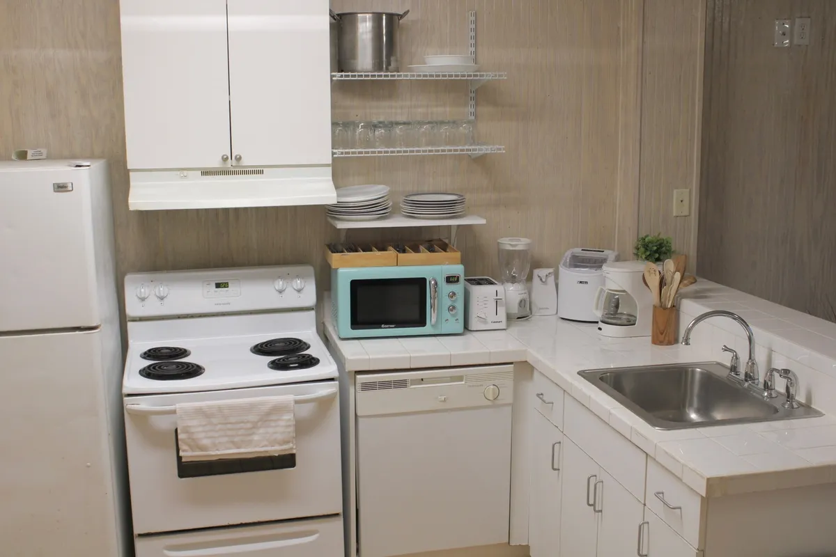 A small kitchen area with a stove, sink, microwave, and dishwasher. The arrangement emphasizes easy access to cooking and cleaning essentials, creating a functional and homey space for guests.